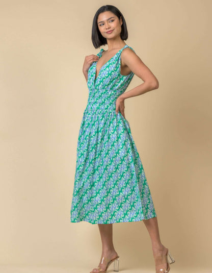 Woman wearing a green and white patterned dress against a beige background