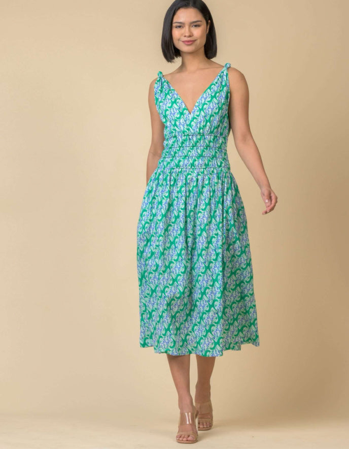 Woman wearing a green floral dress against a beige background