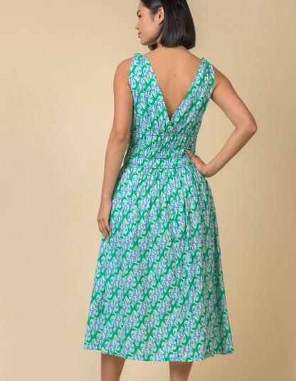 Woman wearing a green and white patterned dress against a beige background