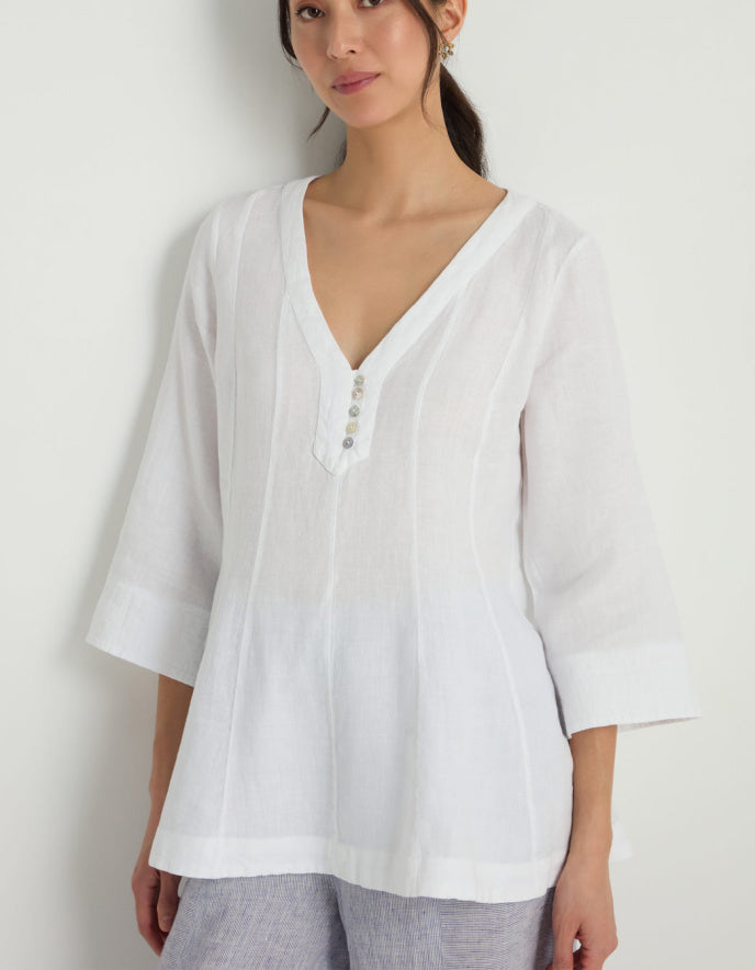 Woman wearing a white linen tunic against a white background