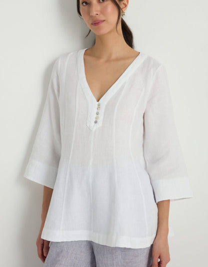 Woman wearing a white linen tunic against a white background