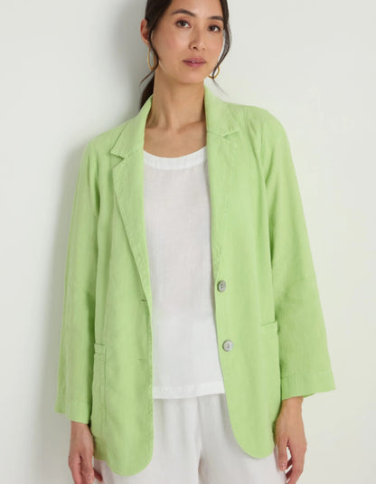 Woman wearing a light green blazer over a white top on a plain background