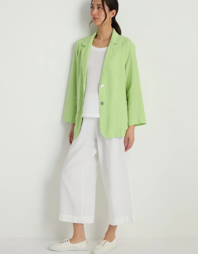 Person wearing a light green jacket over a white top and pants on a white background