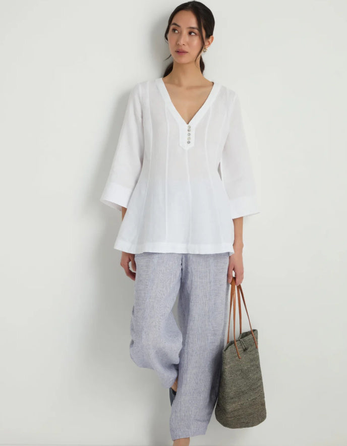 Woman wearing a white linen tunic against a white background