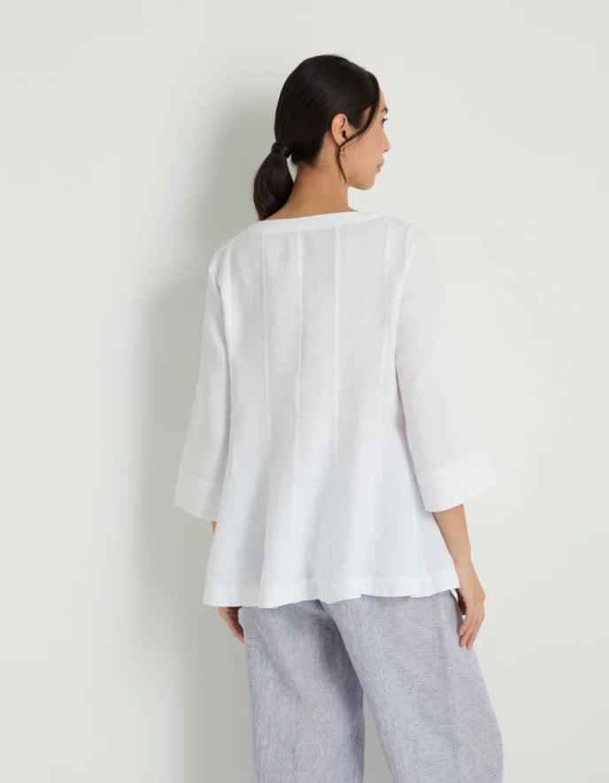 Woman wearing a white linen tunic against a white background