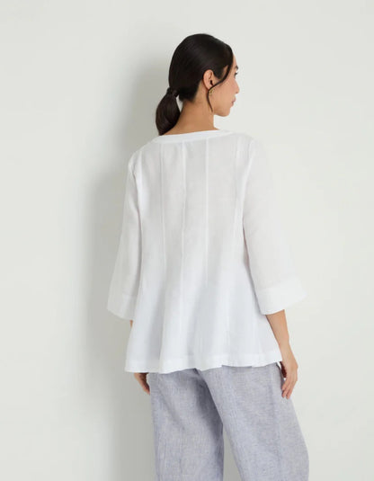 Woman wearing a white linen tunic against a white background