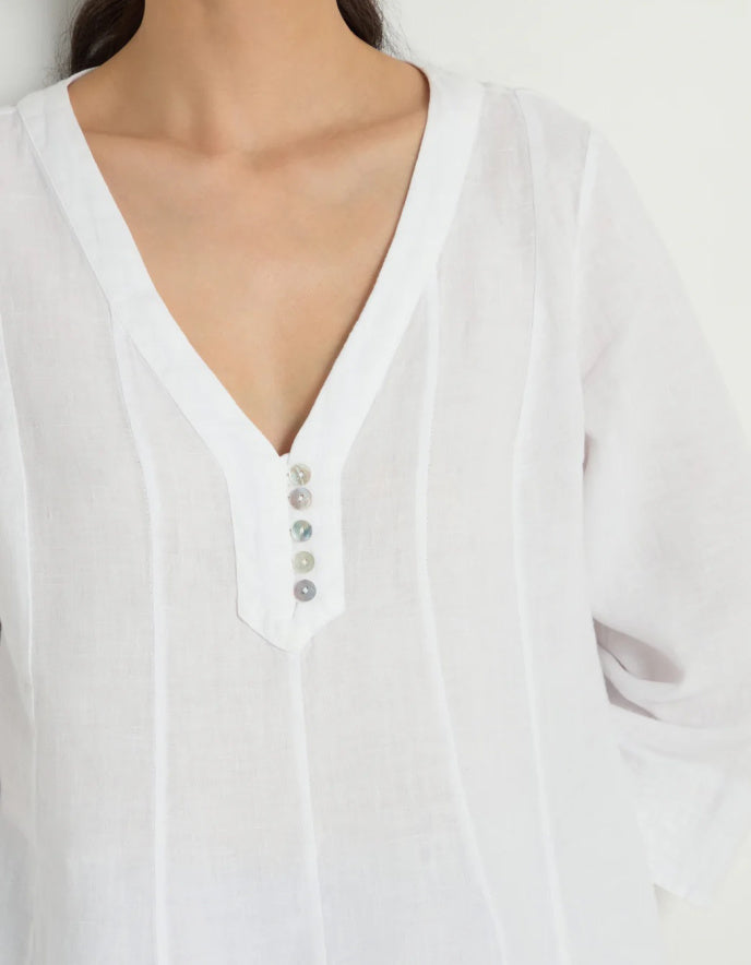 Woman wearing a white linen tunic against a white background