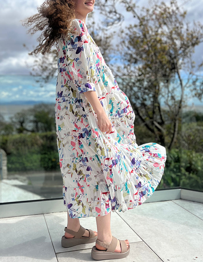 midi length white cotton summer dress with tiered skirt and elbow length sleeves with pretty floral print in pink and purple