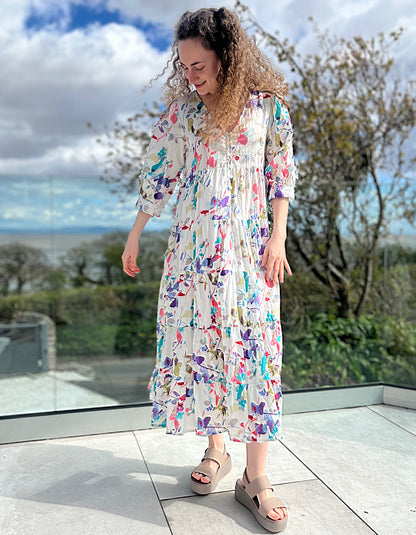 midi length white cotton summer dress with tiered skirt and elbow length sleeves with pretty floral print in pink and purple