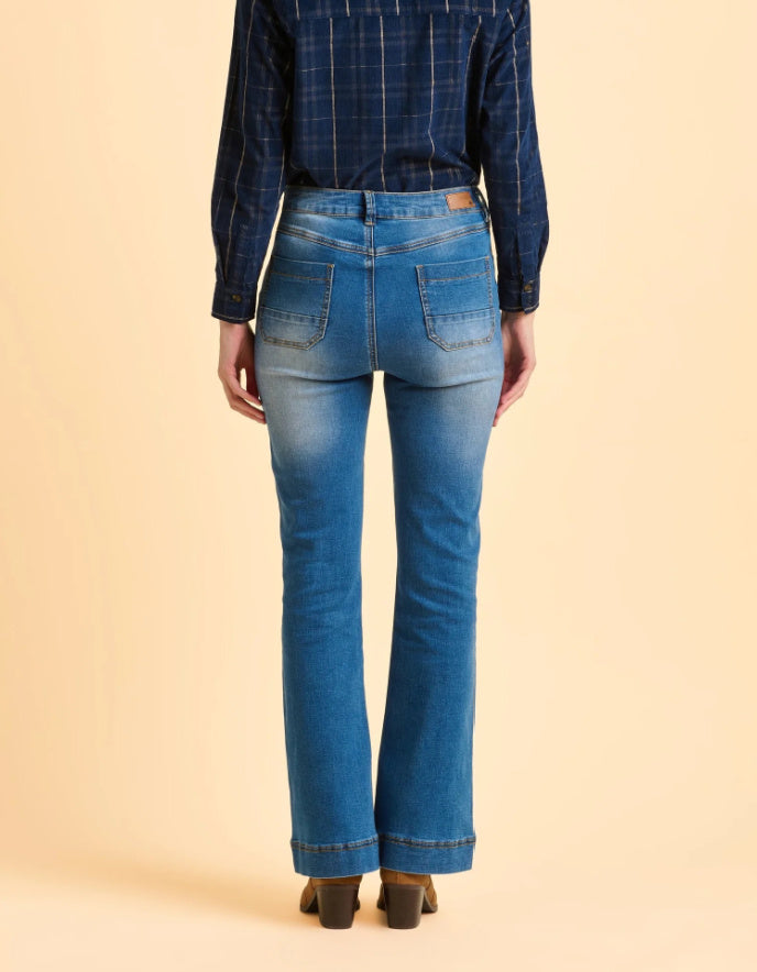 Person wearing blue jeans and a plaid shirt on a beige background