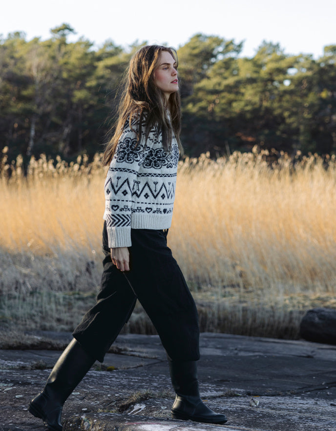 Woman wearing a cream Fairisle patterned scandi sweater on a white background