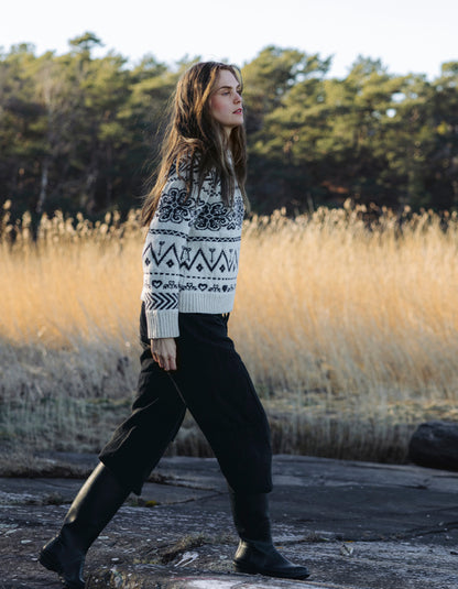 Woman wearing a cream Fairisle patterned scandi sweater on a white background