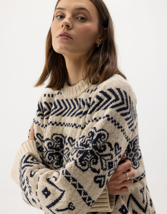 Woman wearing a cream Fairisle patterned scandi sweater on a white background