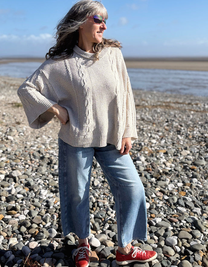 woman wearing cotton cable sweater on a beach