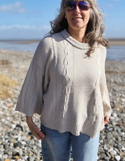 woman wearing cotton cable sweater on a beach