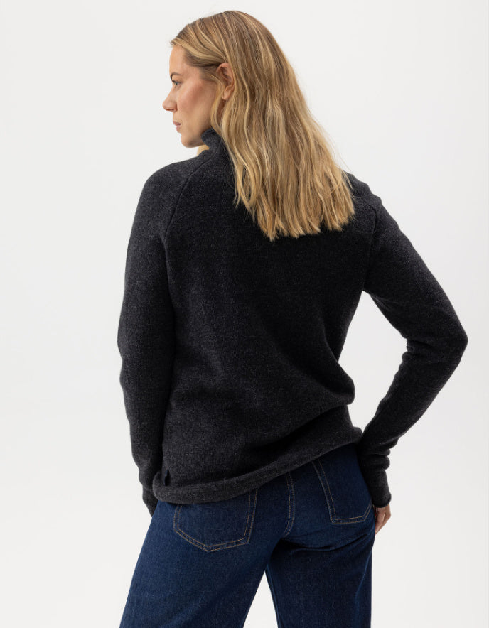 Person wearing a black fleece jacket and blue jeans on a white background