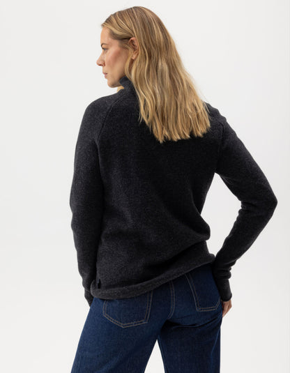 Person wearing a black fleece jacket and blue jeans on a white background