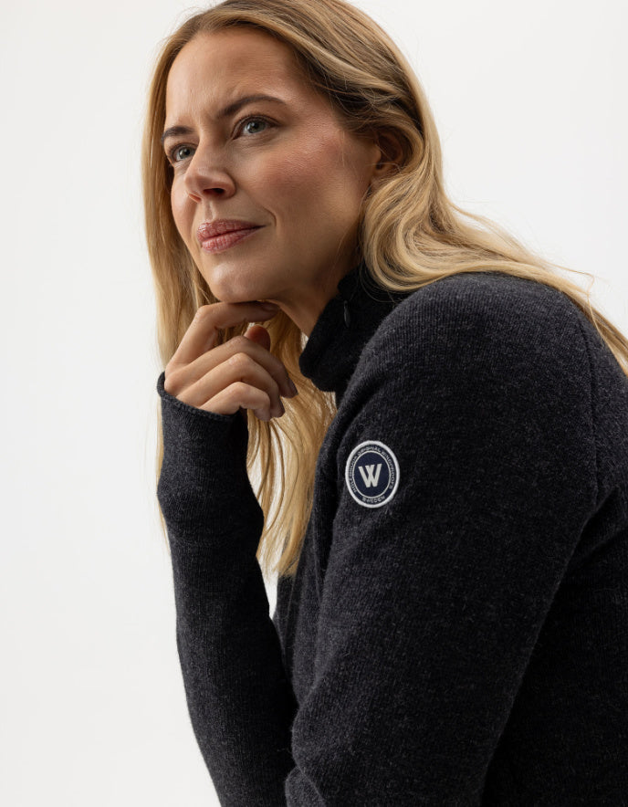 Woman wearing a dark gray sweater with a logo on a white background