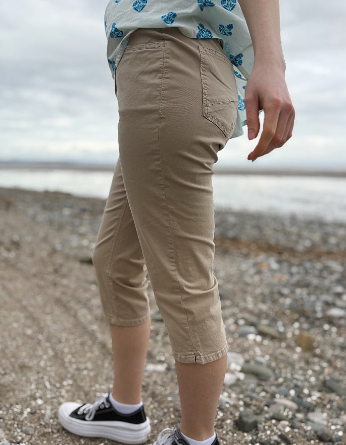 Person wearing beige capri pants on a pebbly beach