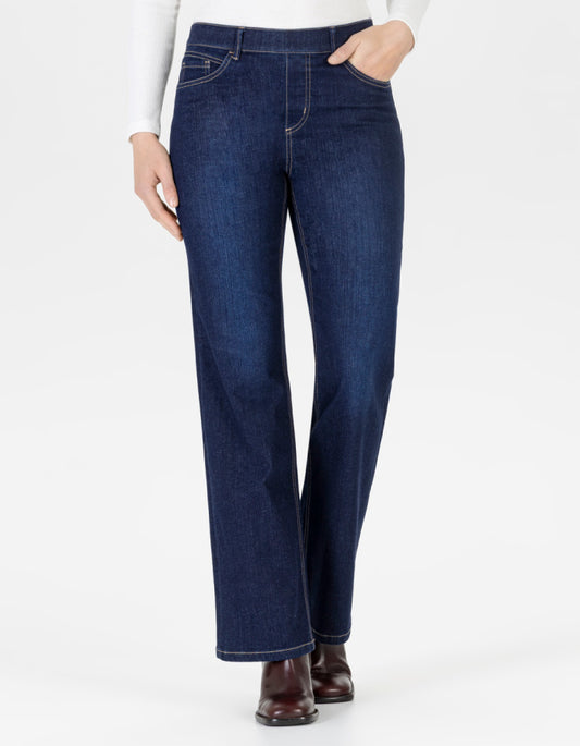 A woman wearing dark blue straight-leg denim jeans with a white long-sleeve top and brown boots, shown from the waist down against a plain white studio background.