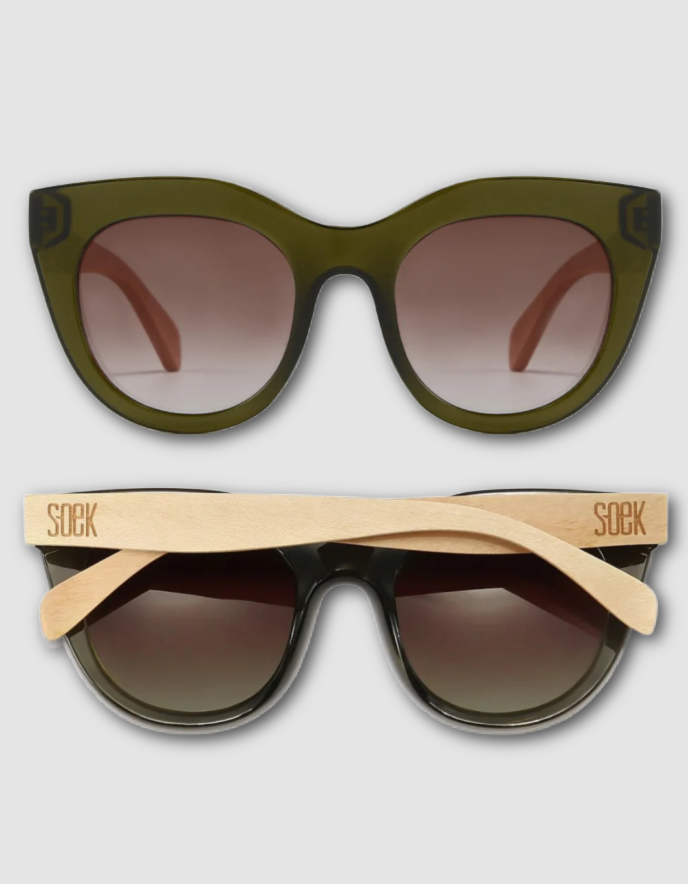 Two pairs of sunglasses shown on a light grey background: one with an olive green acetate frame and brown gradient lenses, and one with a black acetate frame and natural bamboo temple arms branded 'SOEK'.