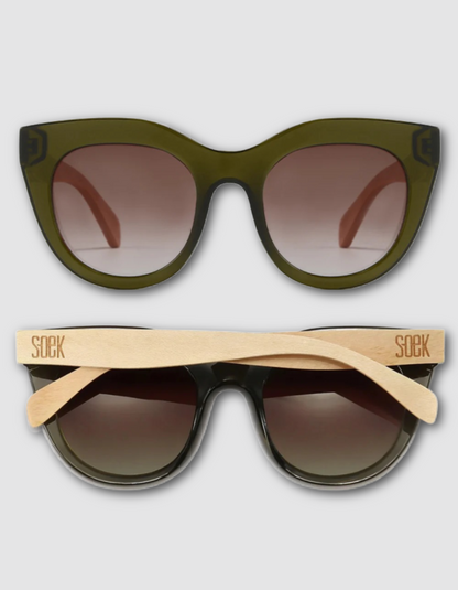 Two pairs of sunglasses shown on a light grey background: one with an olive green acetate frame and brown gradient lenses, and one with a black acetate frame and natural bamboo temple arms branded 'SOEK'.