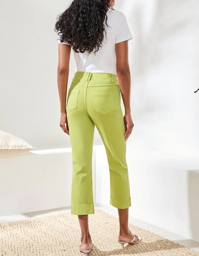 Person wearing green pants and a white top in a minimal indoor setting