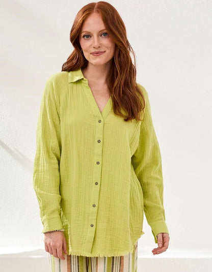 Woman wearing a light green button-up shirt against a white background