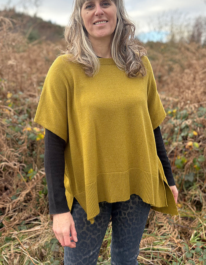 Woman wearing a mustard yellow poncho in a natural setting