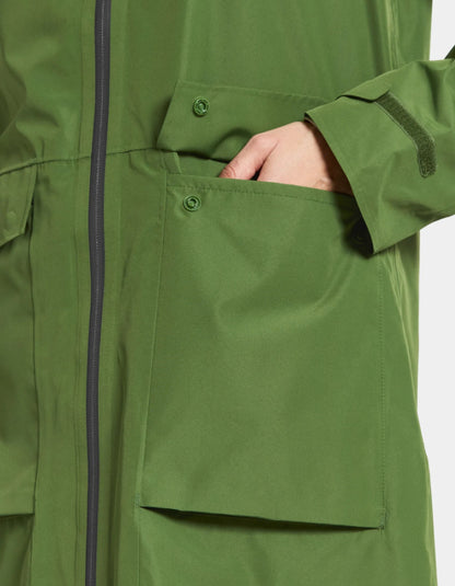 Close-up of a green raincoat with a hand in the pocket on a white background