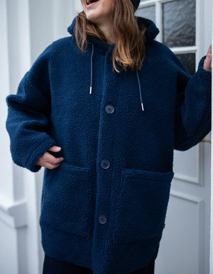 Person wearing a blue fleece jacket with a white door in the background