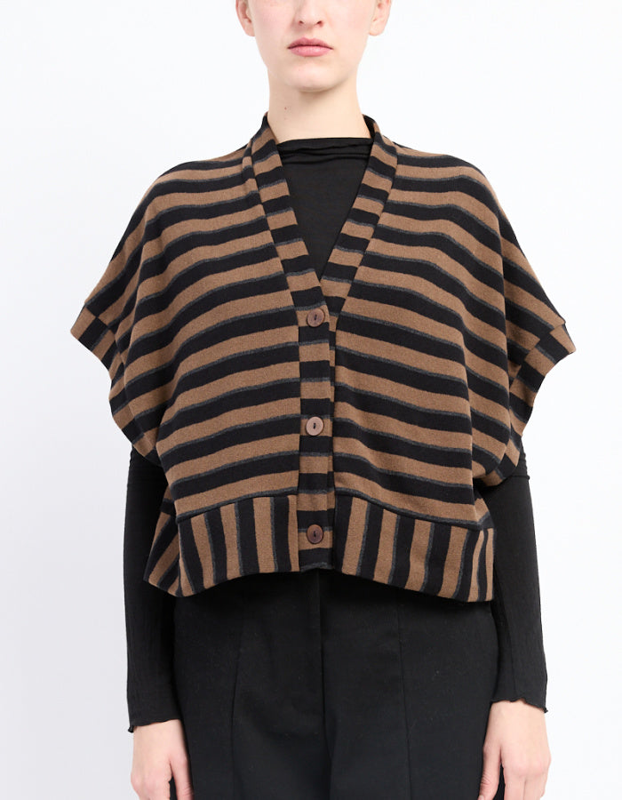 A model wearing a brown and black striped knit poncho cardigan over a black long-sleeve top and black trousers, photographed against a plain white studio background.
