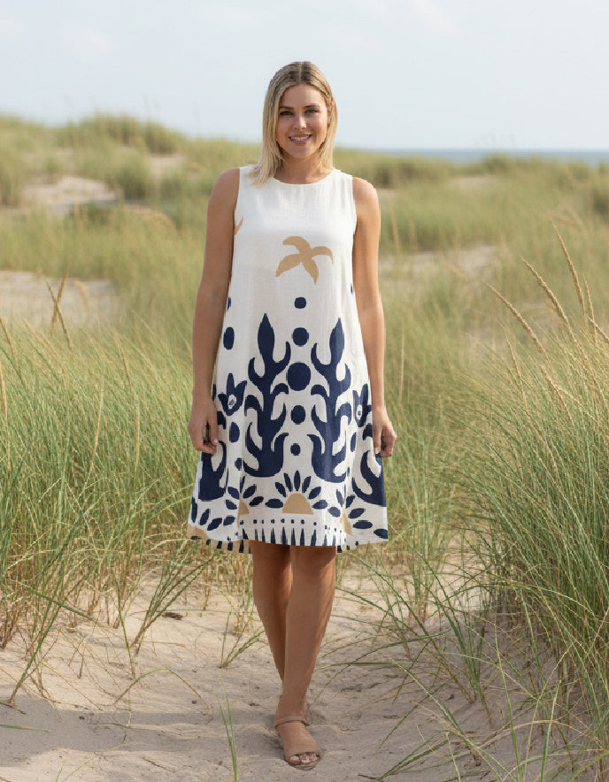 woman wearing white cotton shift dress with navy graphic print in the sand dunes