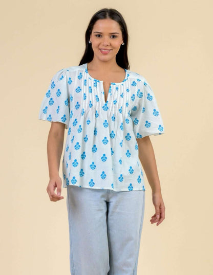 Woman wearing a white blouse with blue floral patterns on a beige background