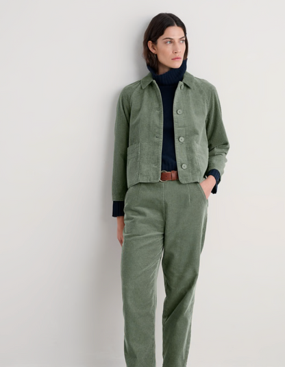 Person wearing sage green boxy fit cotton cord jacket with a white background