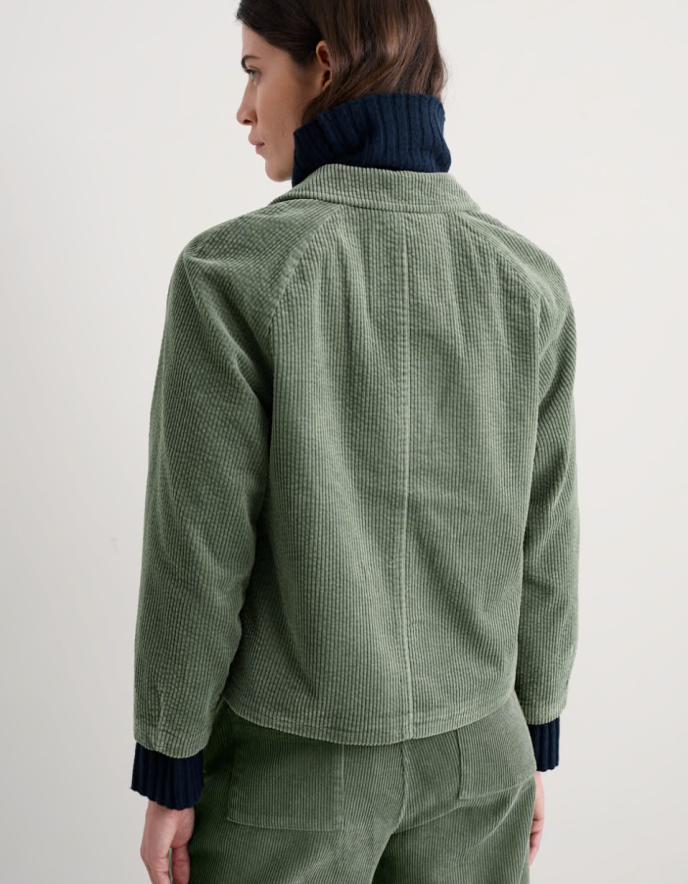 Person wearing sage green boxy fit cotton cord jacket with a white background