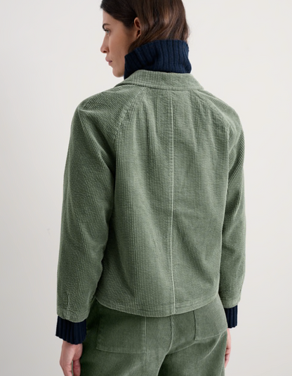 Person wearing sage green boxy fit cotton cord jacket with a white background