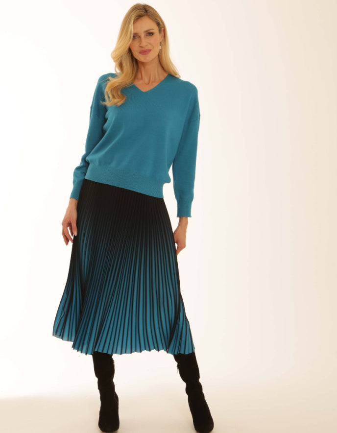 Woman wearing a blue sweater and pleated skirt on a white background