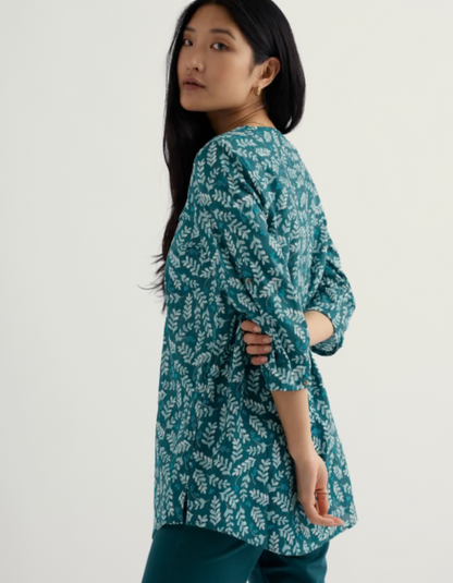 Woman wearing a teal floral patterned dress on a white background