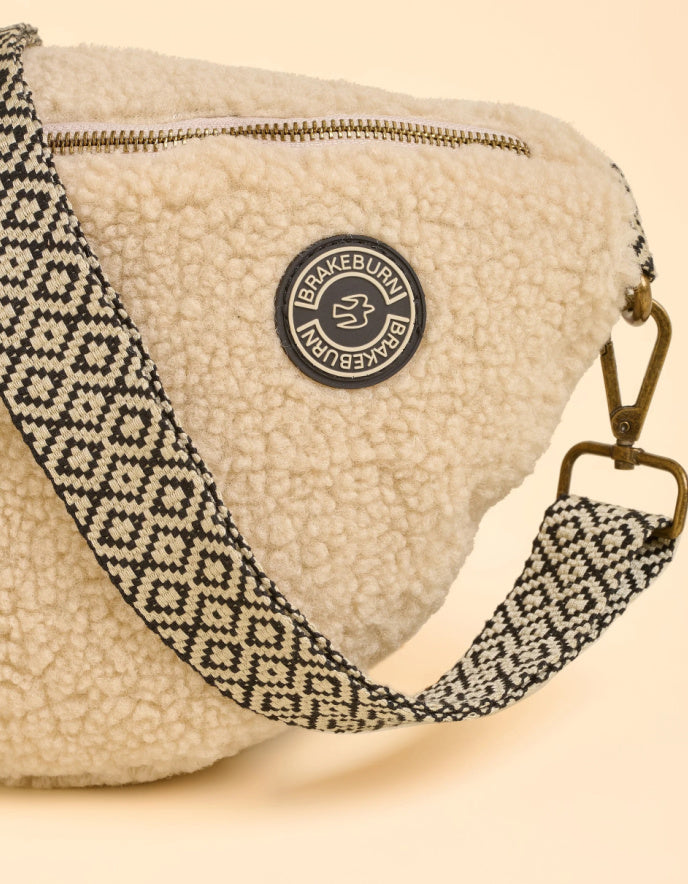 Beige fleece pouch with patterned strap and Brakeburn label on a beige background