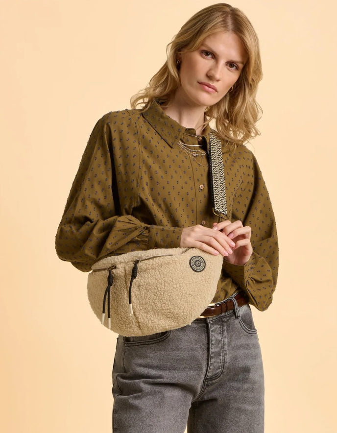 Woman holding a beige bag against a beige background