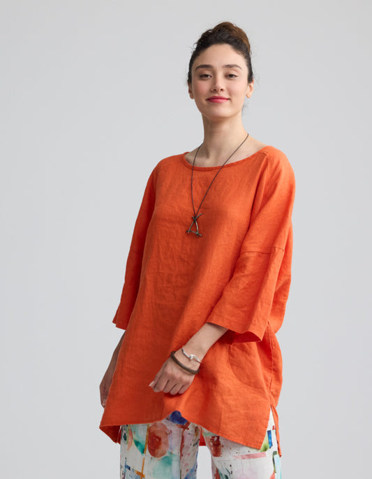 Woman wearing an orange linen top against a plain background