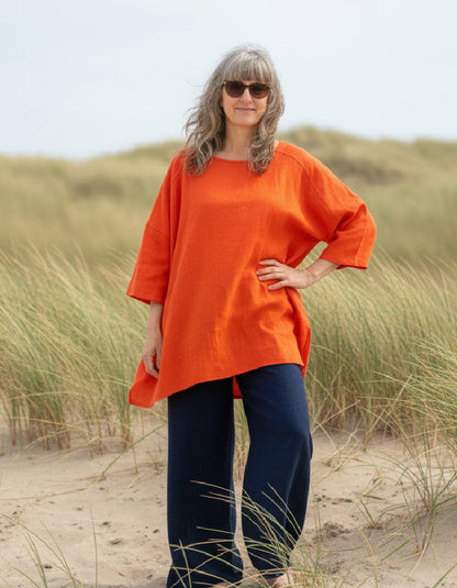 woman wearing orange linen tunic on a beach