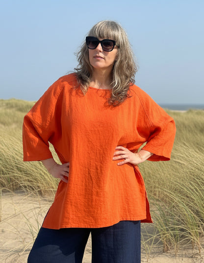 woman wearing orange linen tunic on a beach