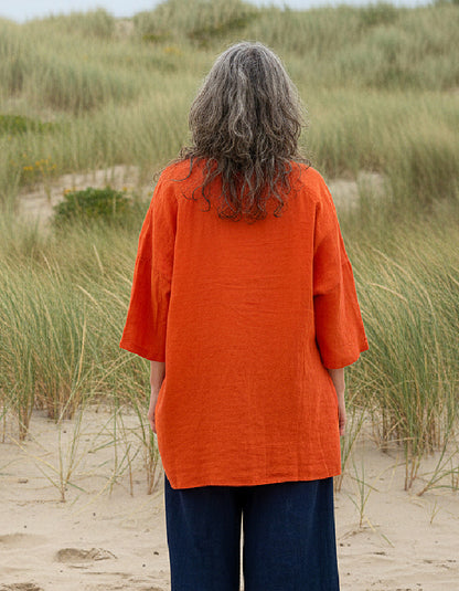 woman wearing orange linen tunic on a beach