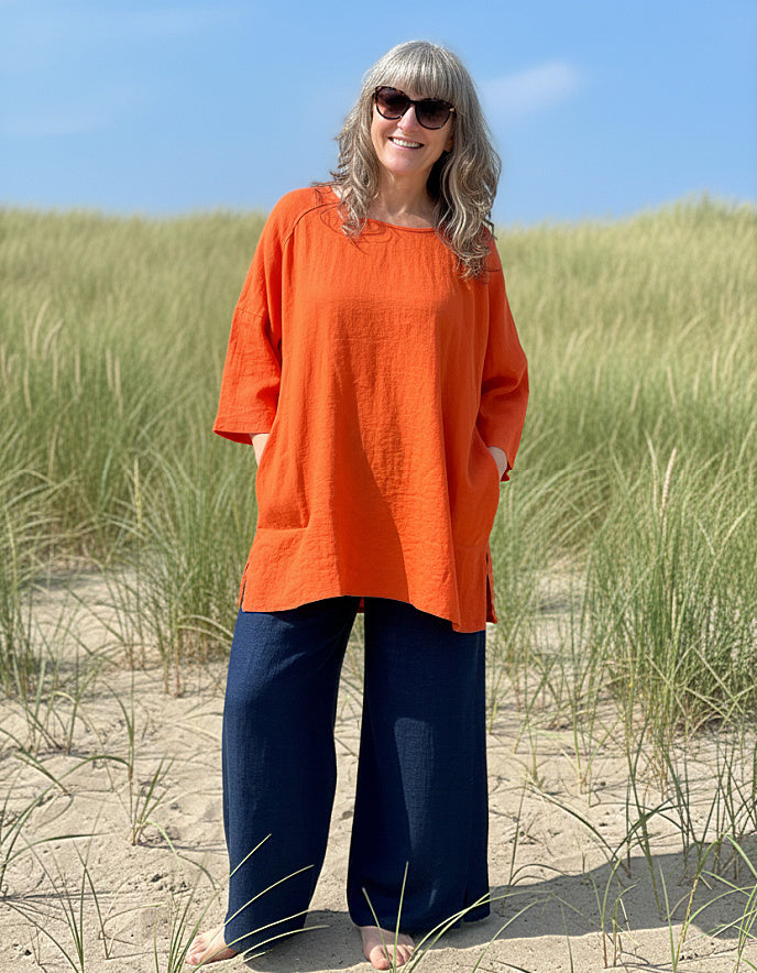 woman wearing orange linen tunic on a beach