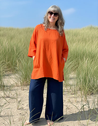 woman wearing orange linen tunic on a beach