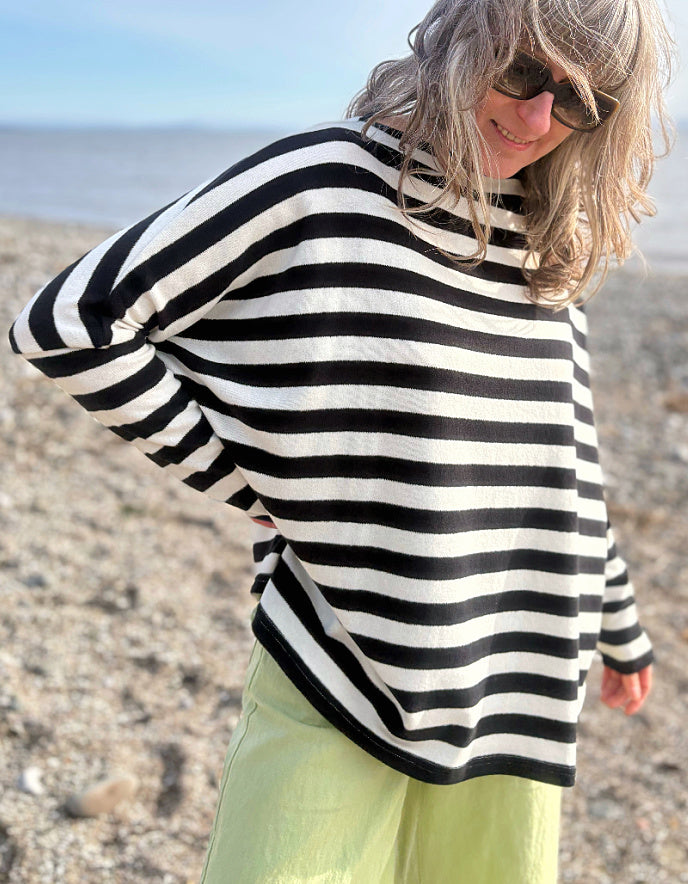 Person wearing a black and white striped sweater on a beach.