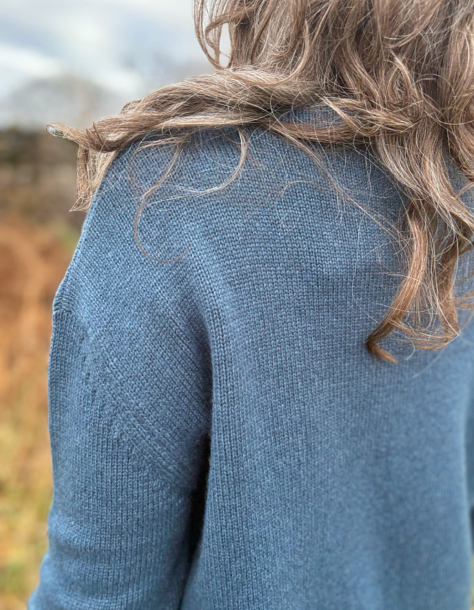 Person wearing a blue sweater with blurred background