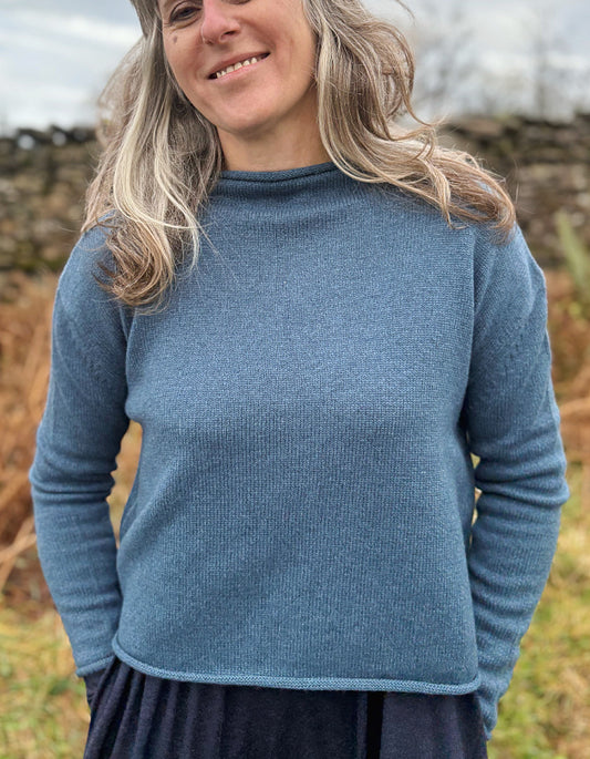 Woman wearing a blue sweater standing outdoors with a natural background